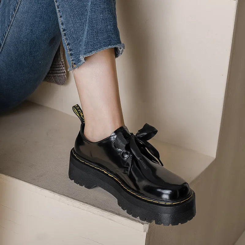 Black and white thick soled women's lace-up shoes with cross straps on a superfine fibre upper.