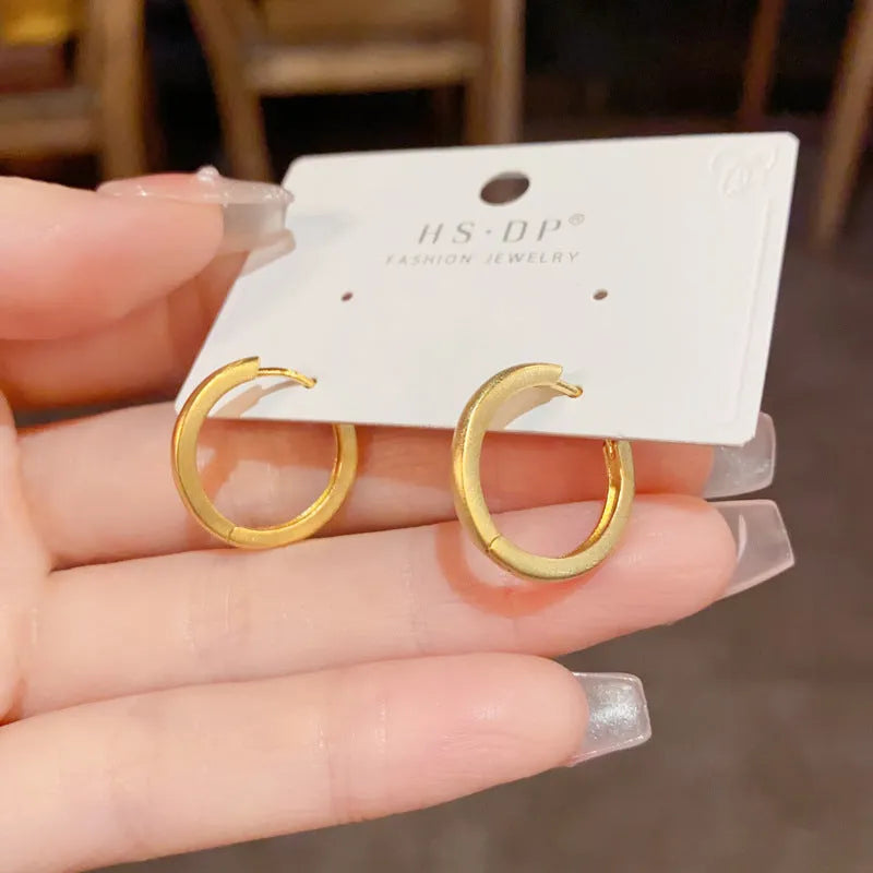 Gold and silver geometric round ear clip earrings for women on a simple background.