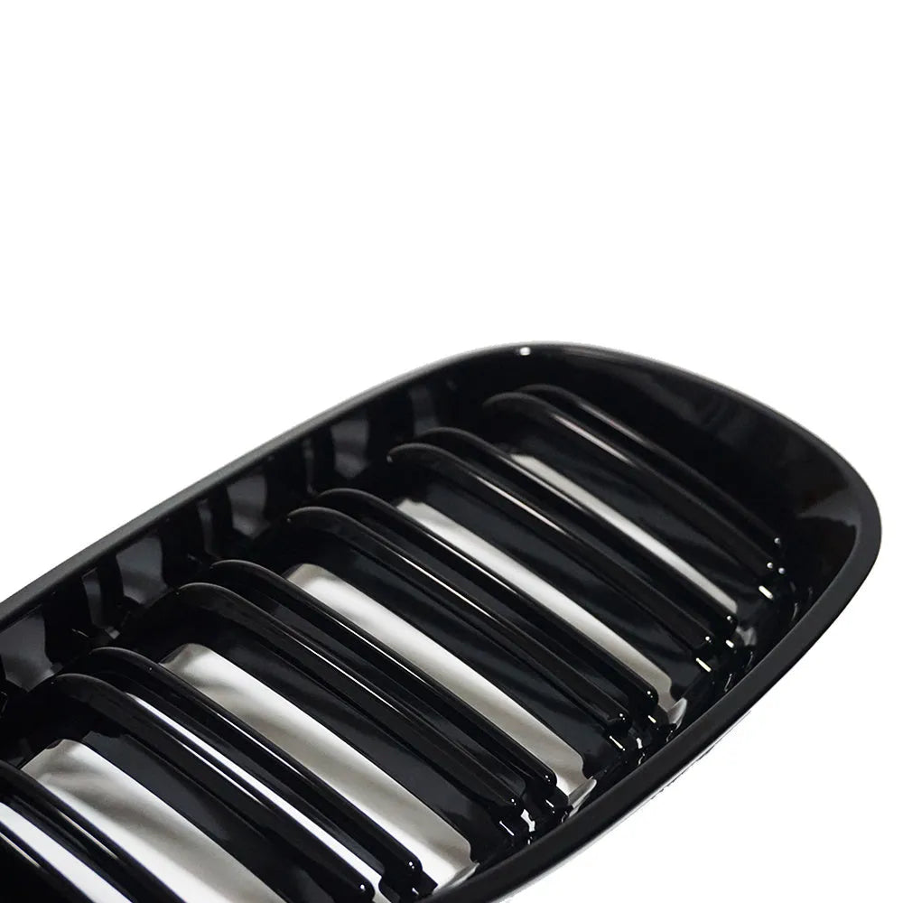 Pair of black carbon fibre pattern front grilles for a BMW 5-Series car.