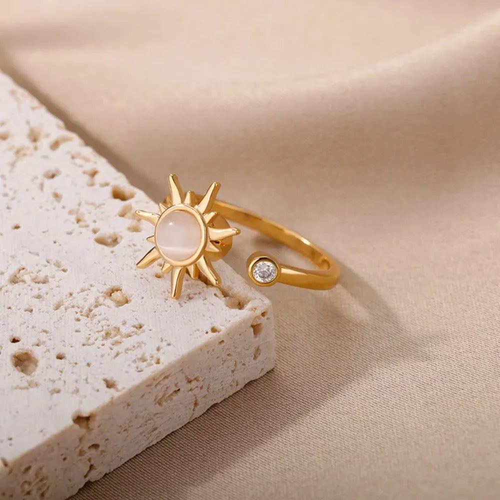 Gold and platinum coloured adjustable geometric decompression ring with rotatable element on a white background.