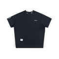Man modelling a loose-fit navy blue waffle knit t-shirt with retro-style white alphabet embroidery on the front.