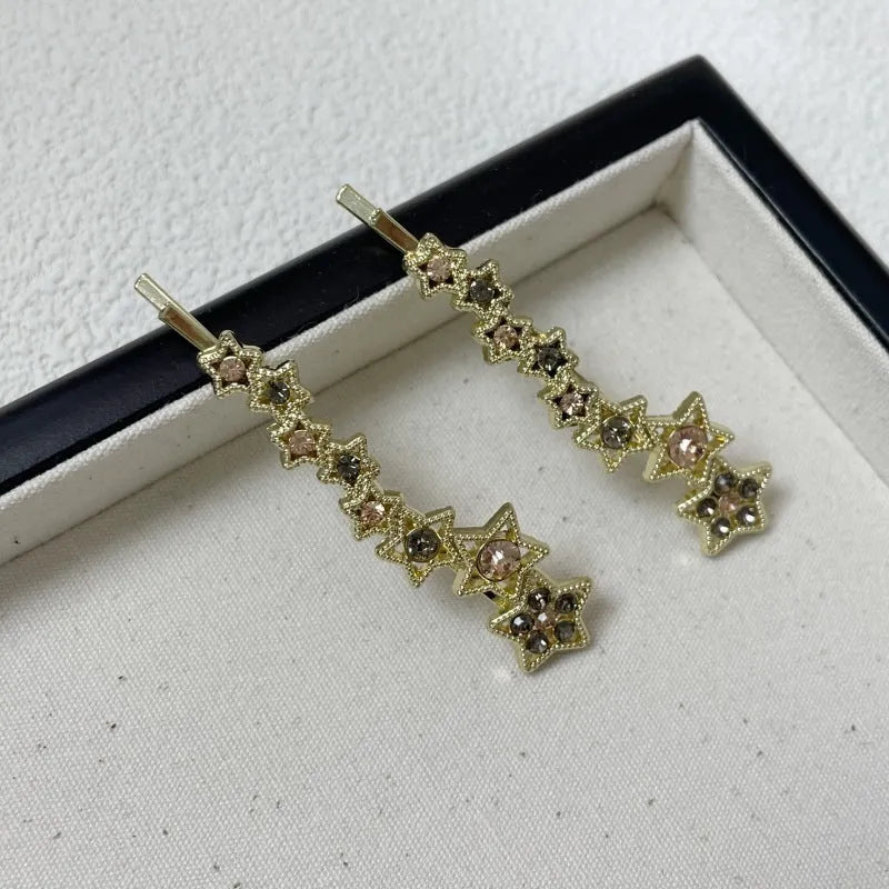 Golden alloy barrette hair clip with rhinestone star decoration and single-word element.