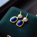 A pair of simple sterling silver earrings featuring a blue lapis lazuli pearl and auspicious patterns.