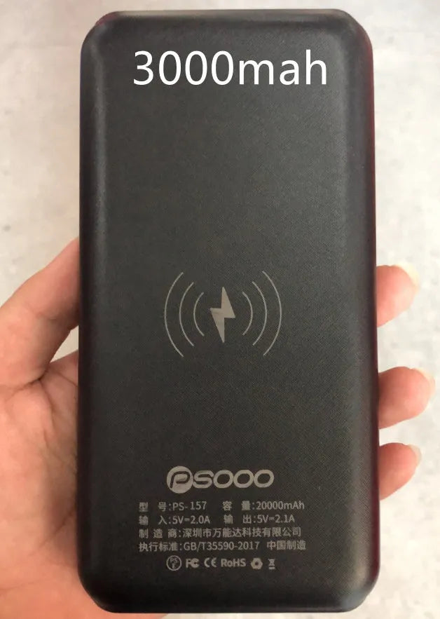 Black portable power bank with Qi wireless charging pad, three USB ports, and an LED flashlight on the front.