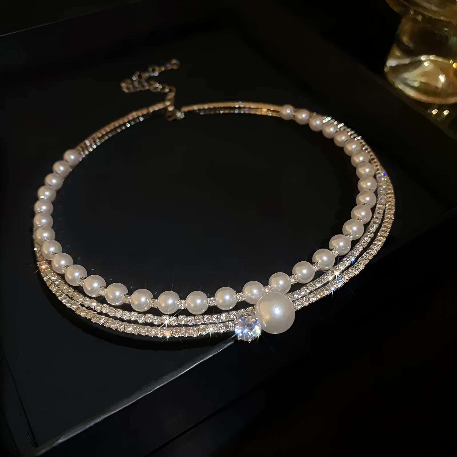 Silver electroplated alloy necklace with round curved geometric shape and ball detail on clavicle chain.