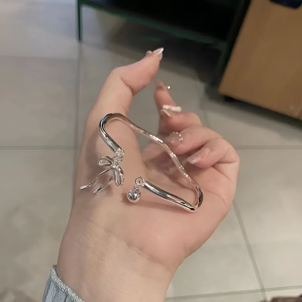 Silver adjustable women's bracelet with a bow bell charm on a zinc alloy bangle.