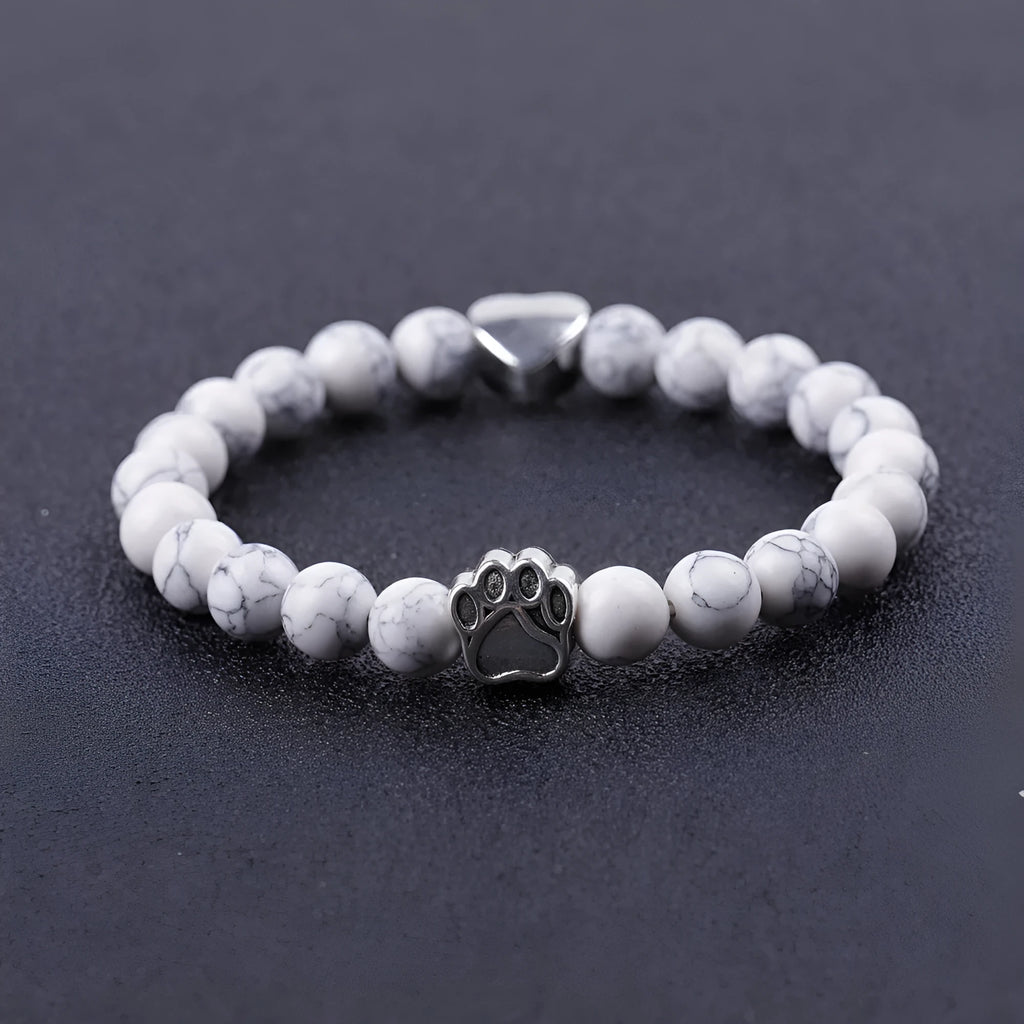 Close-up of a tiger's eye and Indian agate bead bracelet with a central geometric dog's paw charm on a wrist.