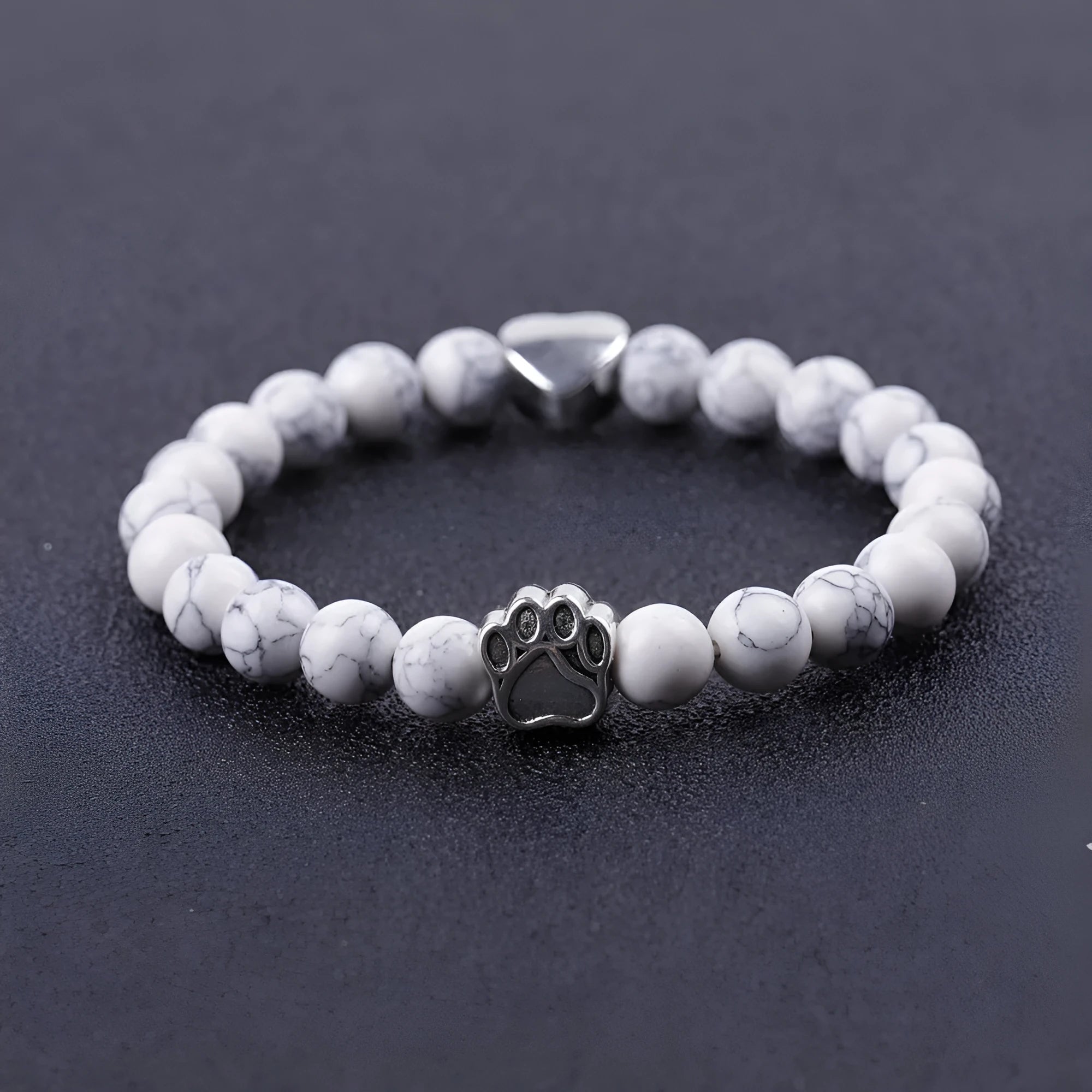 Close-up of a tiger's eye and Indian agate bead bracelet with a central geometric dog's paw charm on a wrist.