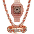 Gold Roman numeral square watch with black mesh band, bracelet, and necklace set on a table.