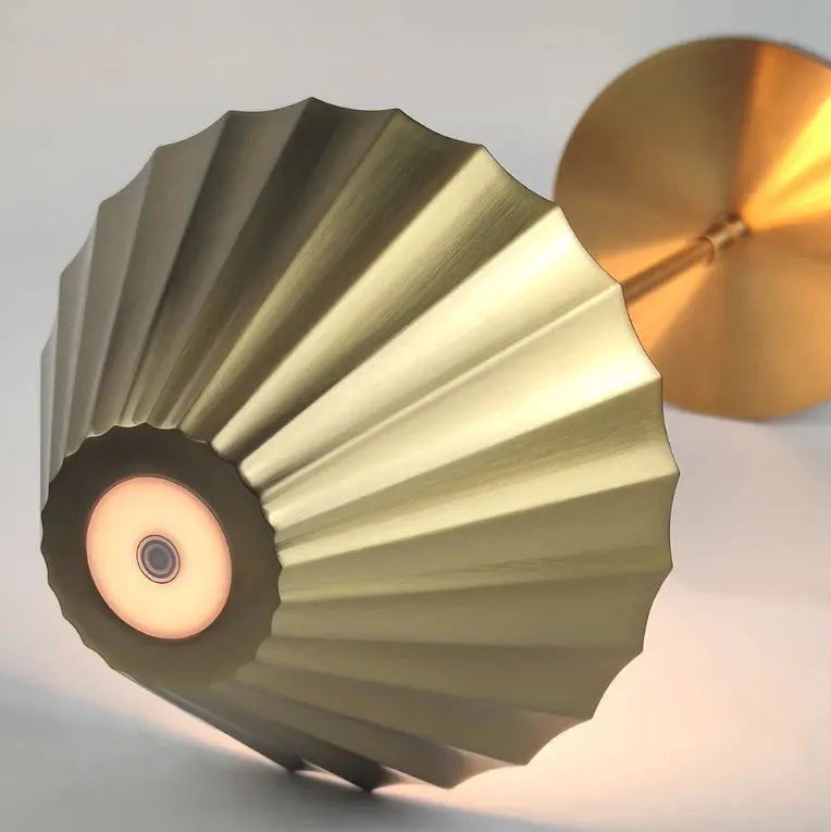 Gold-coloured alloy desk lamp with a fabric shade on a wooden desk.