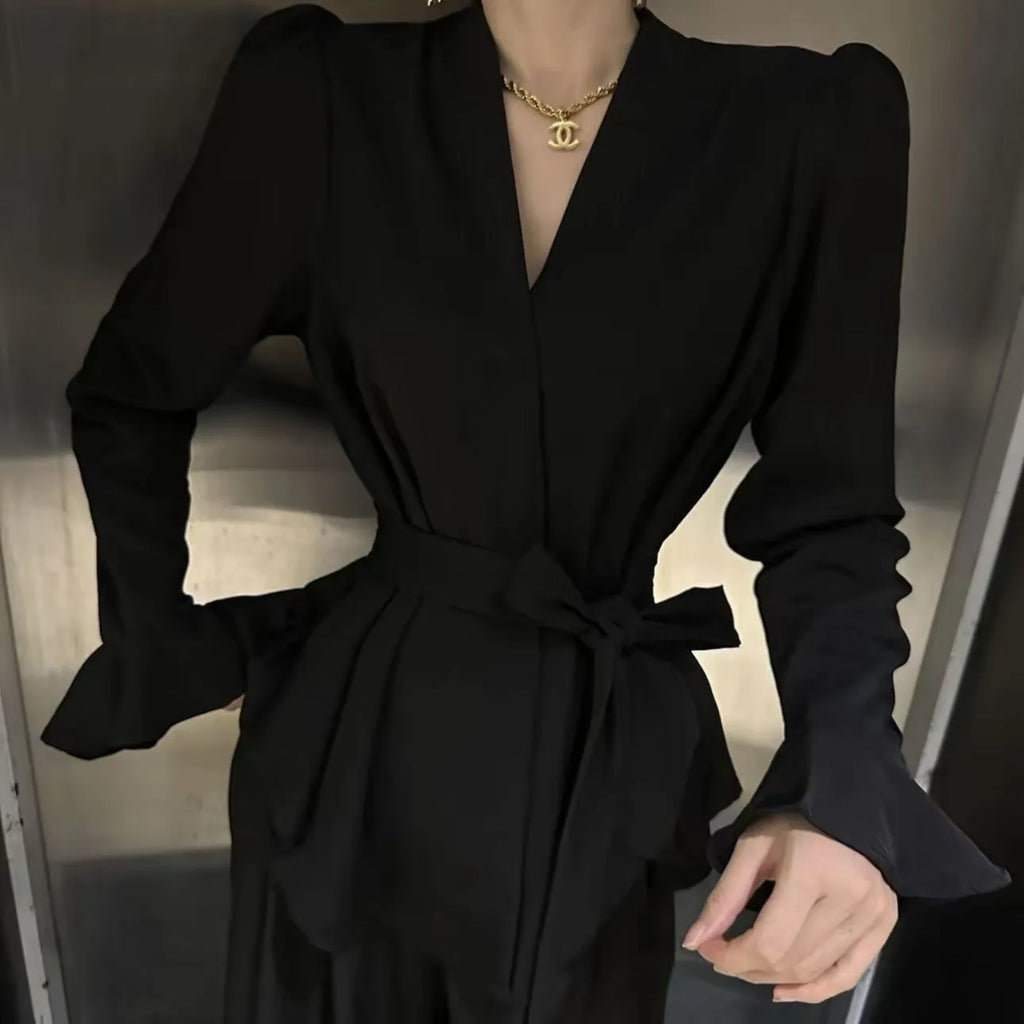 A woman's French-style black shirt with an irregular collar, long bell sleeves, and a tied front closure.