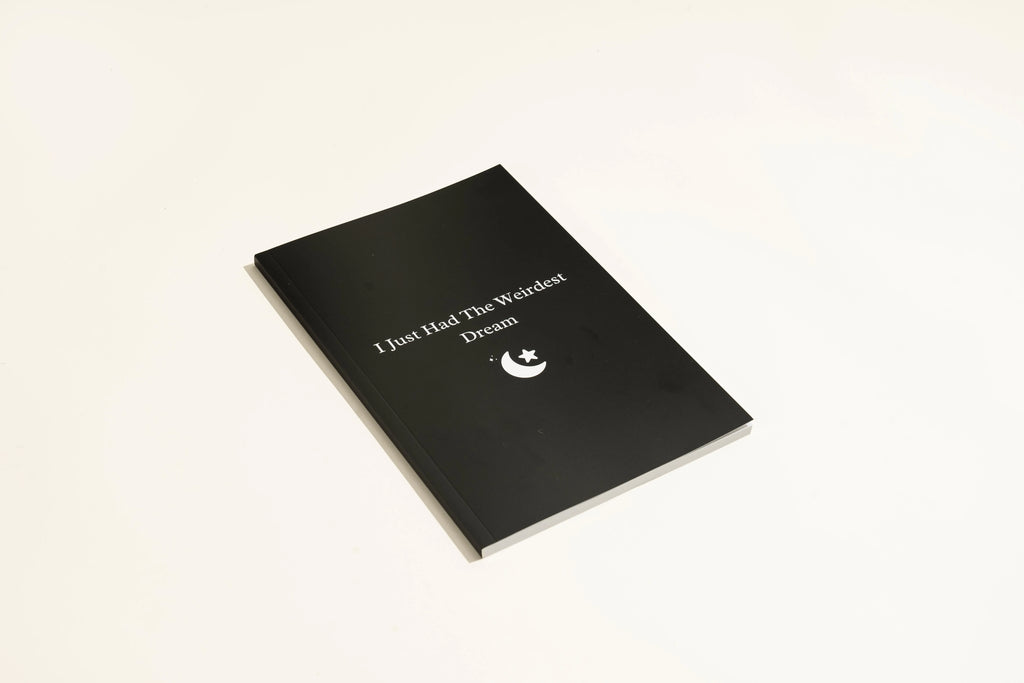 Black hardcover A5 dream journal notebook with plain pages, shown closed and open.