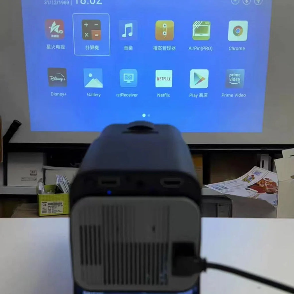 White home projector with carrying handle on a table, set up for wireless gaming projection.