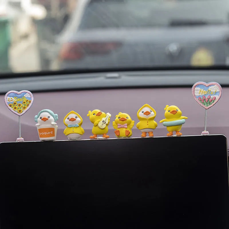 Yellow PVC cartoon duckling car decoration set with six ducks and a Hello sign on a car dashboard.