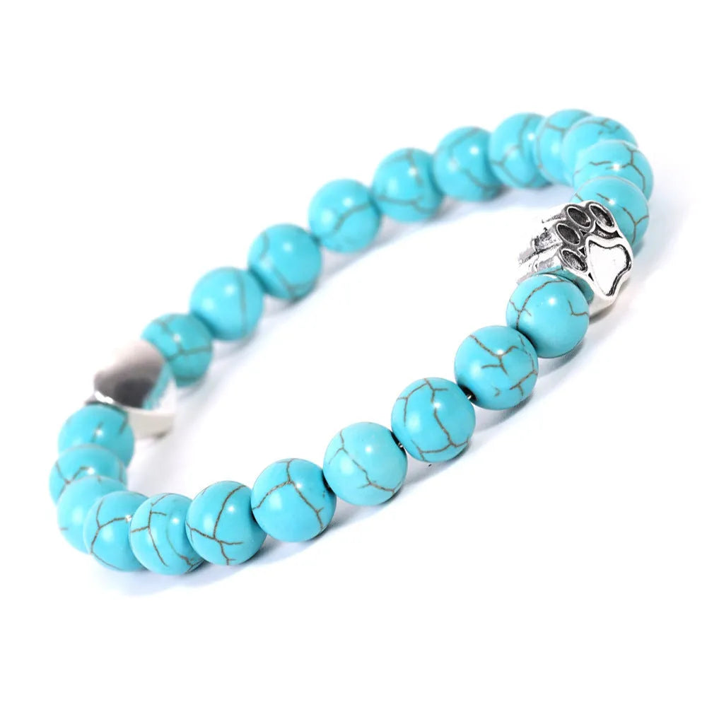 Close-up of a tiger's eye and Indian agate bead bracelet with a central geometric dog's paw charm on a wrist.