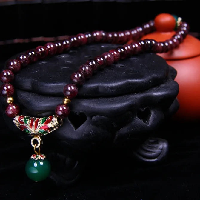 Natural garnet double ring bracelet with a central golden toad charm on an adjustable cord.