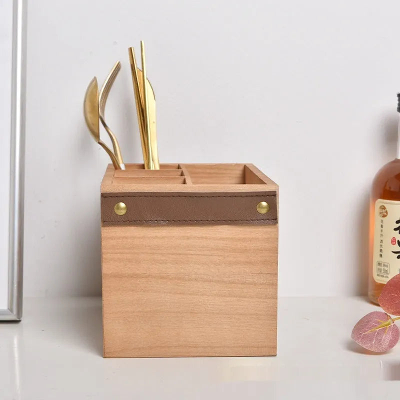 Open-top wooden kitchen storage box with internal grid divider for organising utensils.