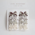 Set of eight children's cloth bow hairclips in assorted colours including beige, blue flowers, and polka dots.