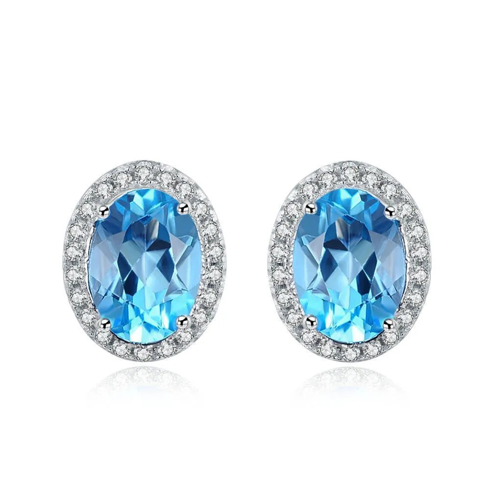 Four-piece sterling silver jewellery set with blue topaz stones: geometric earrings, ring, pendant, and necklace.
