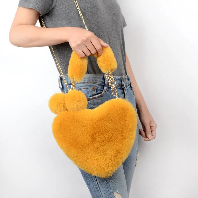 Soft plush heart-shaped women's handbag in a solid colour with a detachable shoulder strap.