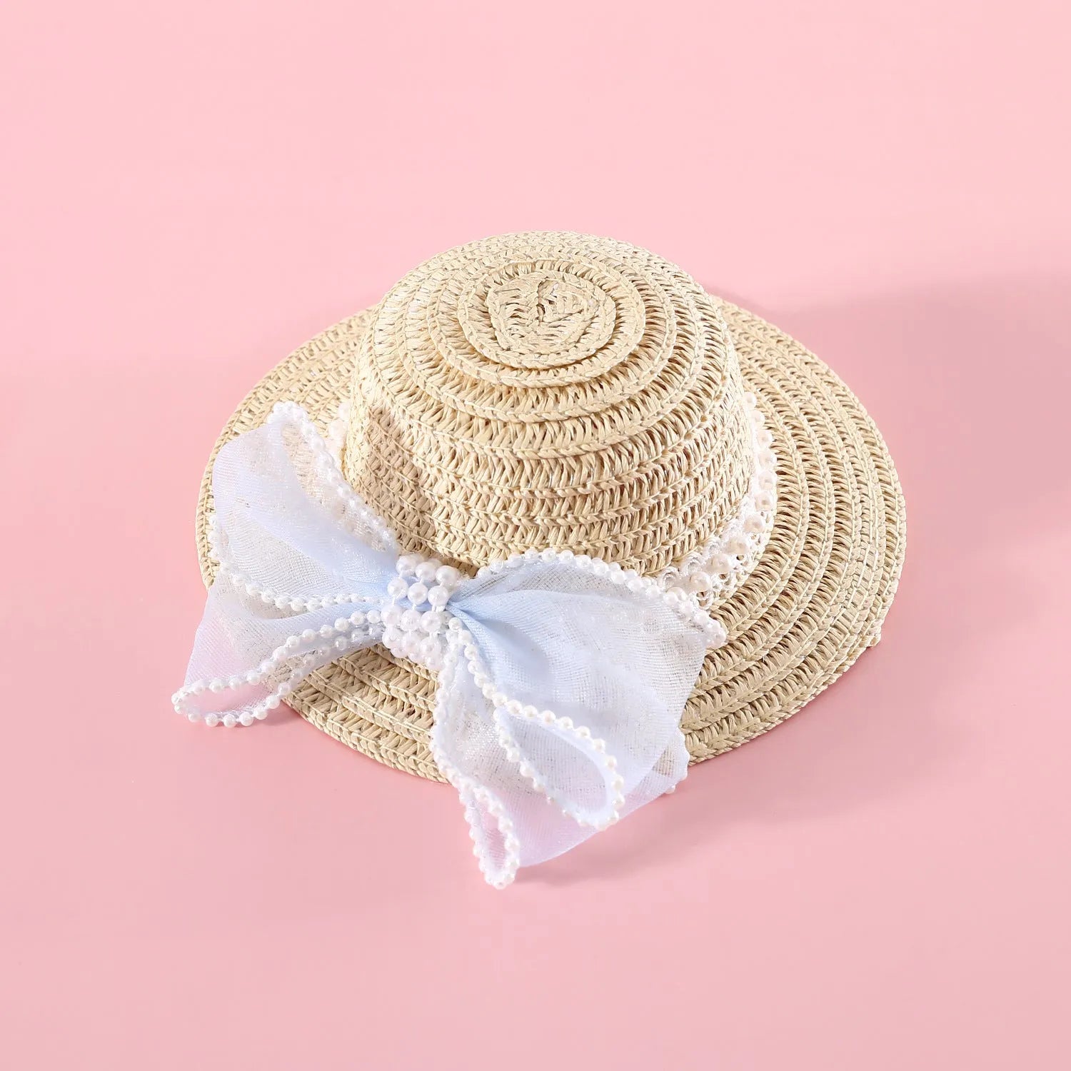 Cat wearing a woven straw hat with a pearl butterfly bow on its head.