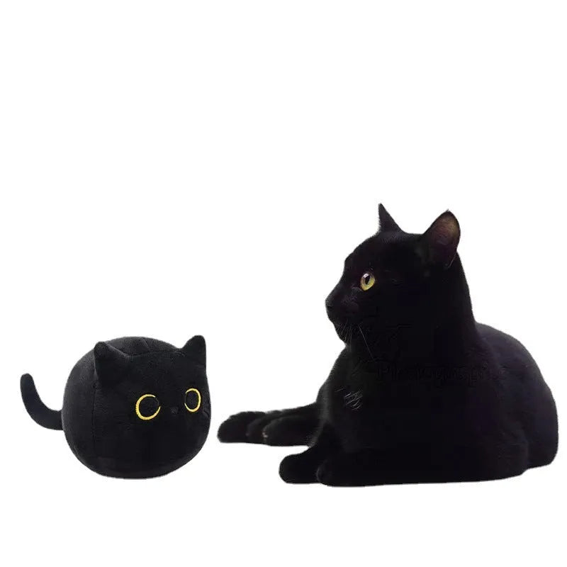 Fluffy black cat plush toy with embroidered face on a soft cushion