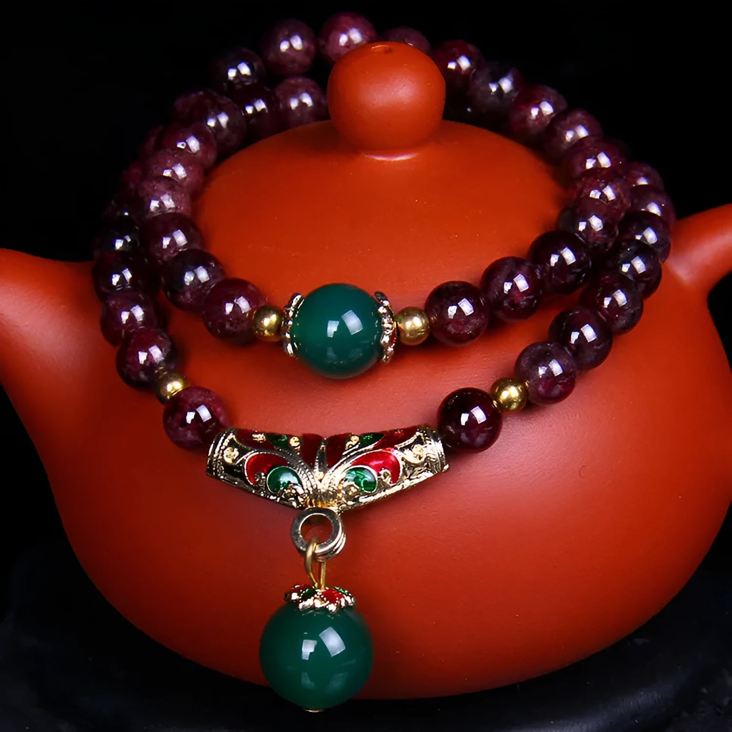 Natural garnet double ring bracelet with a central golden toad charm on an adjustable cord.