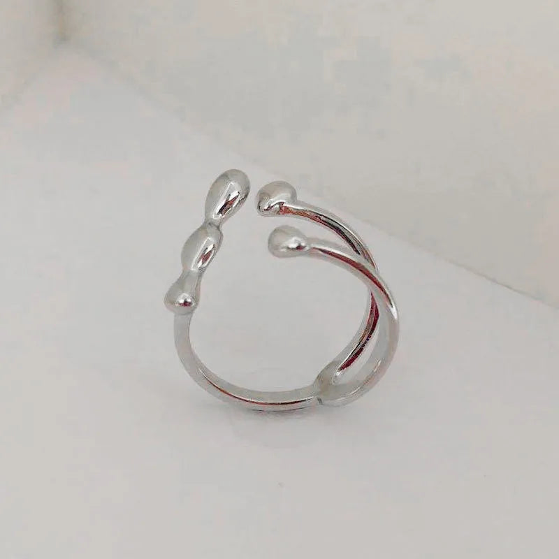 Gold and silver coloured brass opening ring with spherical design on a white background.