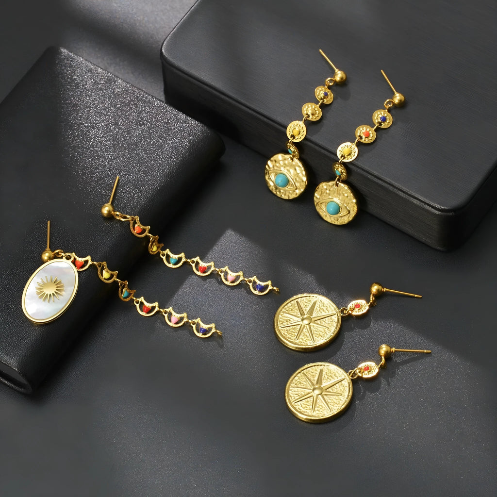 Geometric stainless steel stud earrings showing three colour options: Eight Awn XINGX, Eye, and Shell Sun designs.