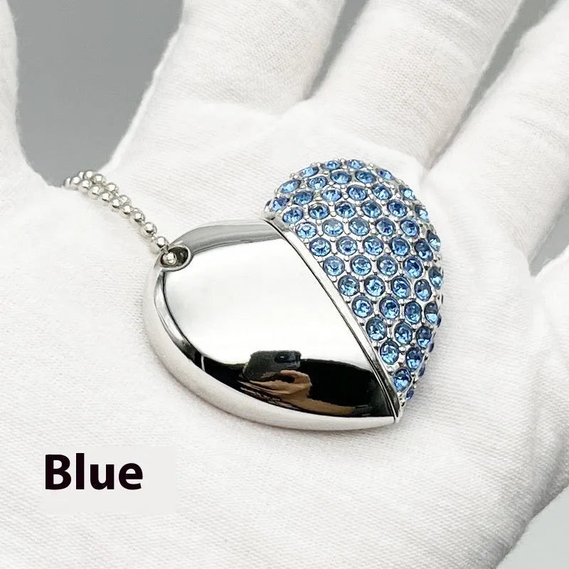 Heart-shaped silver USB drive with brick-like pattern, shown alongside blue and pink coloured versions.