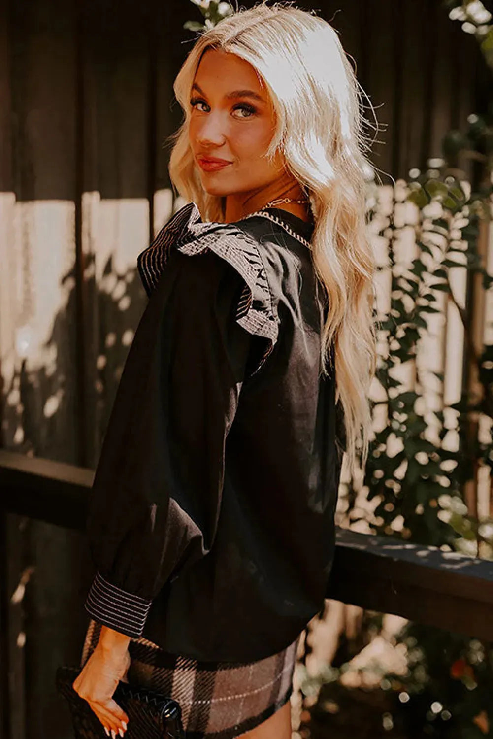 Black women's V-neck blouse with contrast stitching and ruffle detail on long sleeves