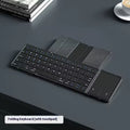 Black folding Bluetooth keyboard with touchpad unfolded next to mobile phone