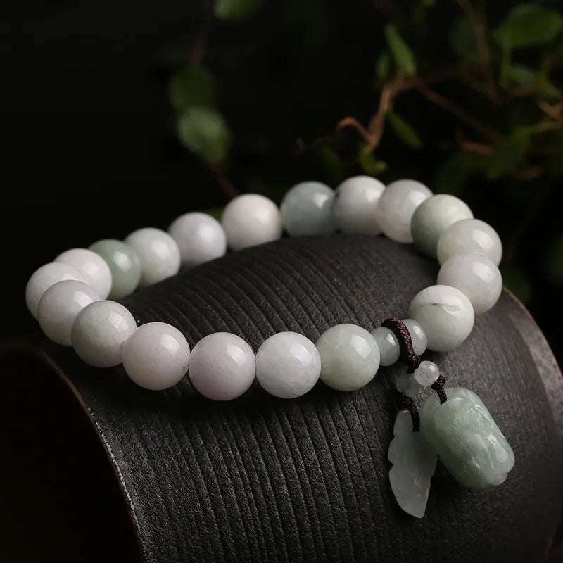 Natural green jade bracelet with a hanging Maitreya Buddha charm on a wrist.