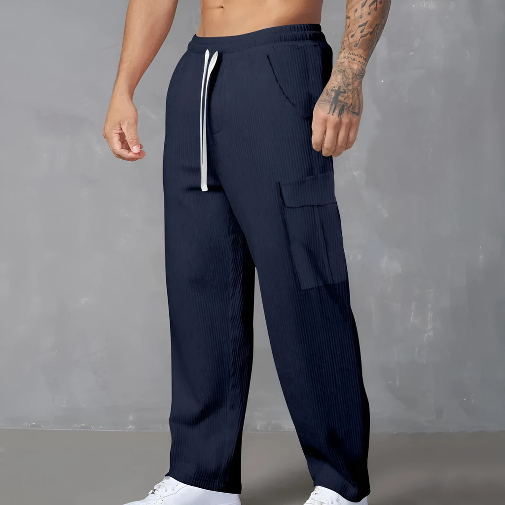 Man wearing navy blue loose-fitting corduroy cargo trousers with a drawstring waist and straight wide legs.