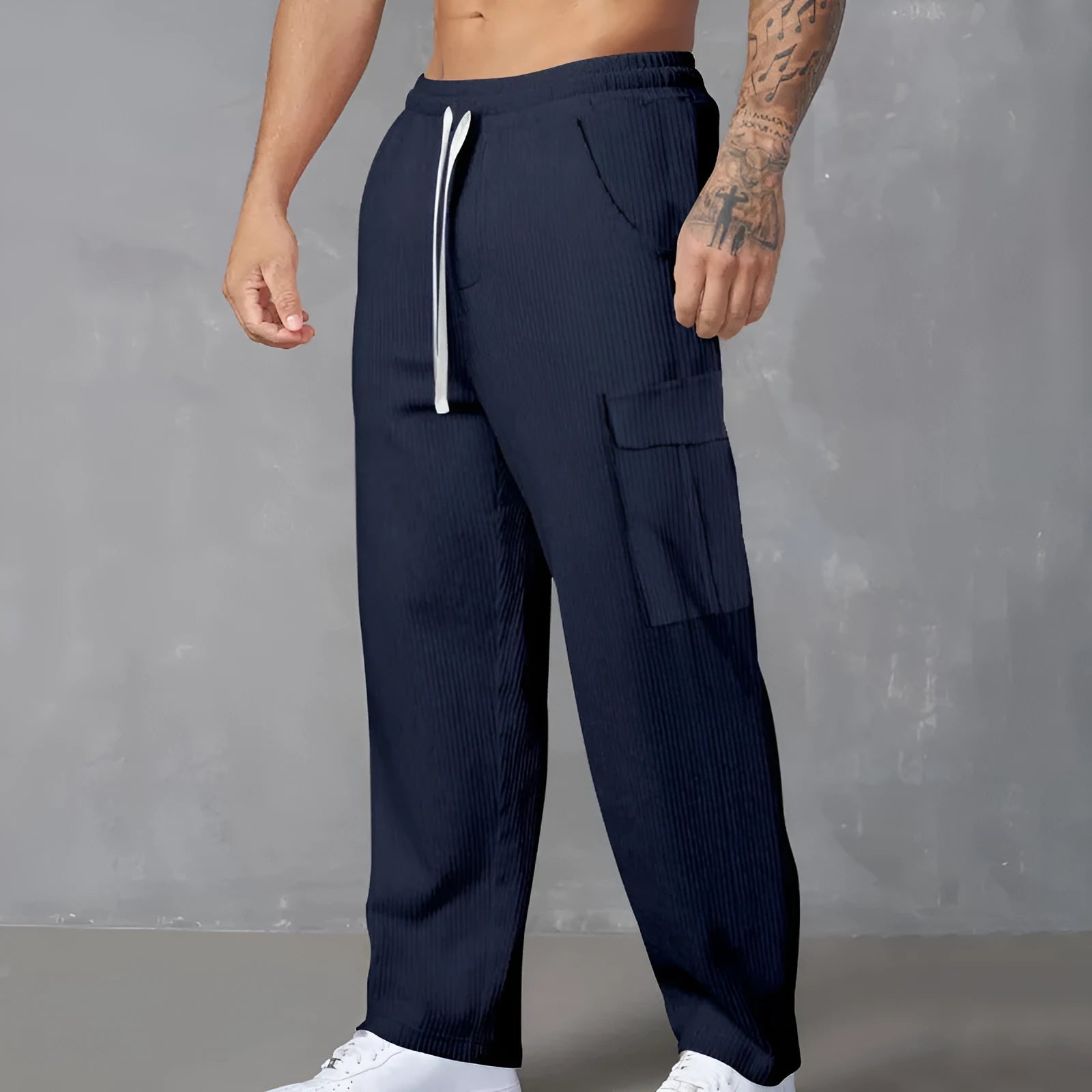Man wearing navy blue loose-fitting corduroy cargo trousers with a drawstring waist and straight wide legs.