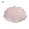 White shell-shaped plastic soap dish for bathroom counter next to pink version.