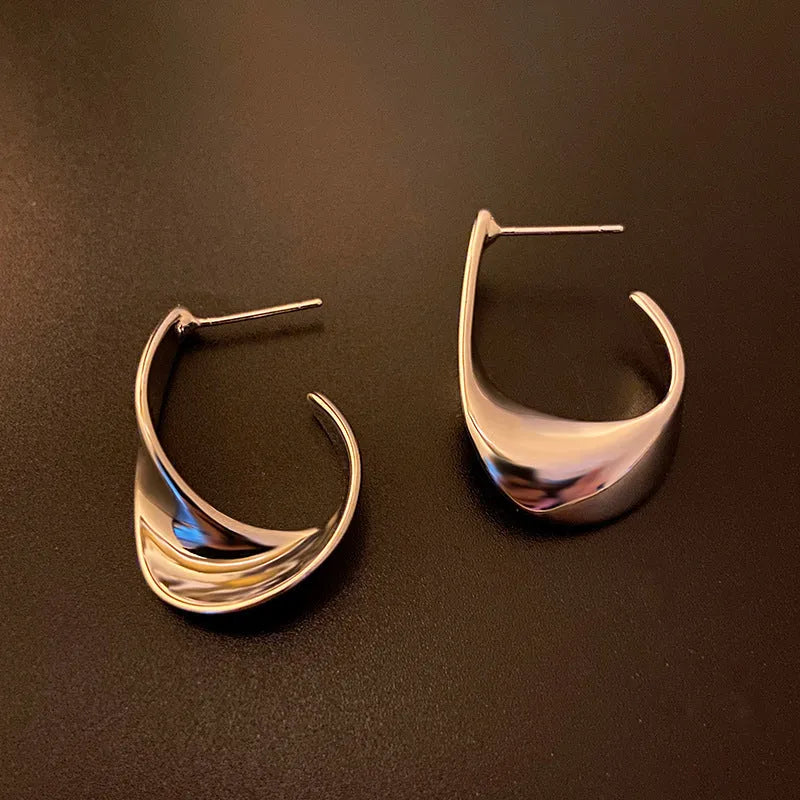 Twisted geometric metal earrings with electroplated gold or silver finish and round shape