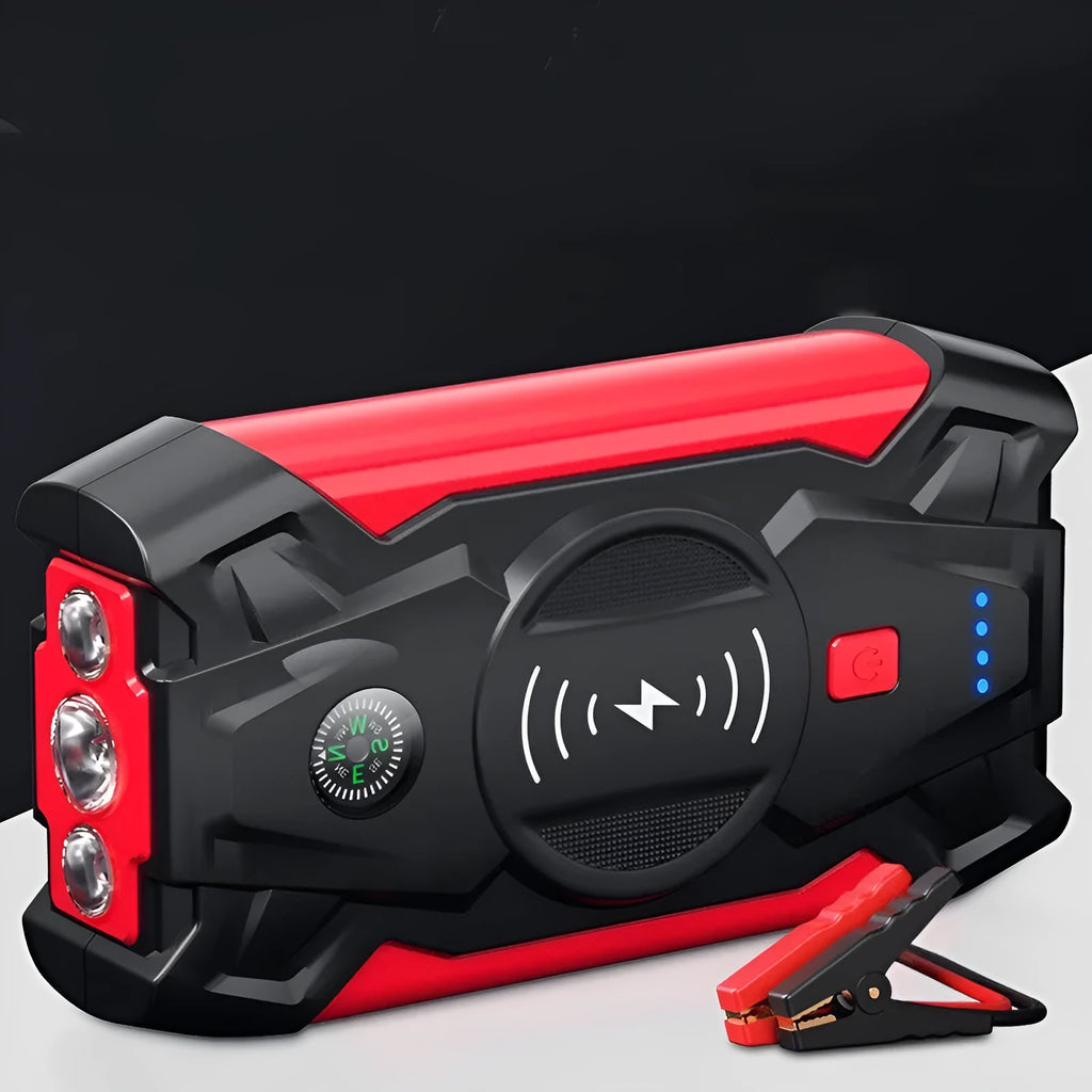 Red portable car jump starter and power bank unit with jumper cables on a table