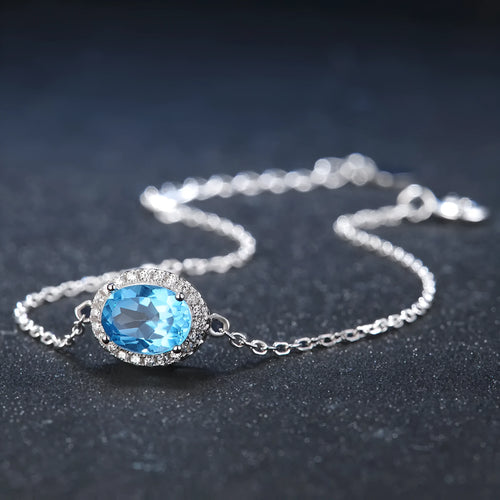 Four-piece sterling silver jewellery set with blue topaz stones: geometric earrings, ring, pendant, and necklace.