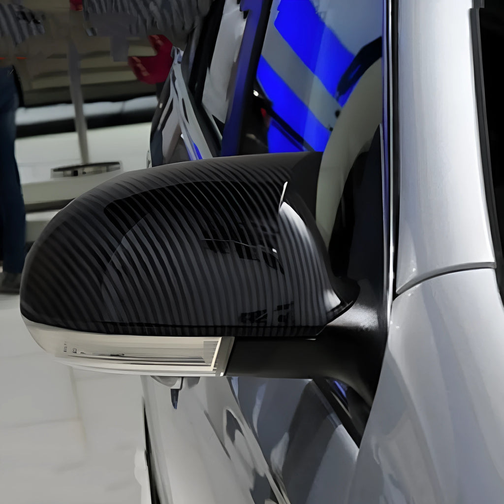 Pair of plastic mirror housings for Volkswagen Sagitar (2006-2011) in black and carbon fibre finishes.