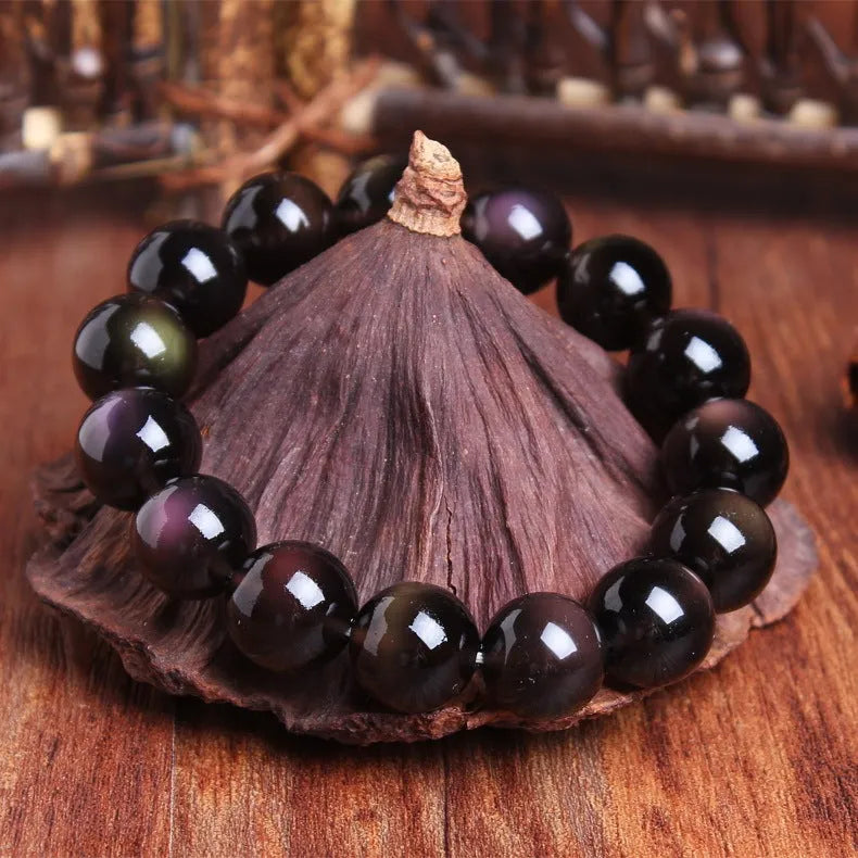 Polished icy obsidian crystal Pi Xiu bracelet with geometric beads on a white background.