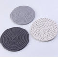 Set of three round grey cotton cord coasters, each 18cm in diameter, on a wooden table.