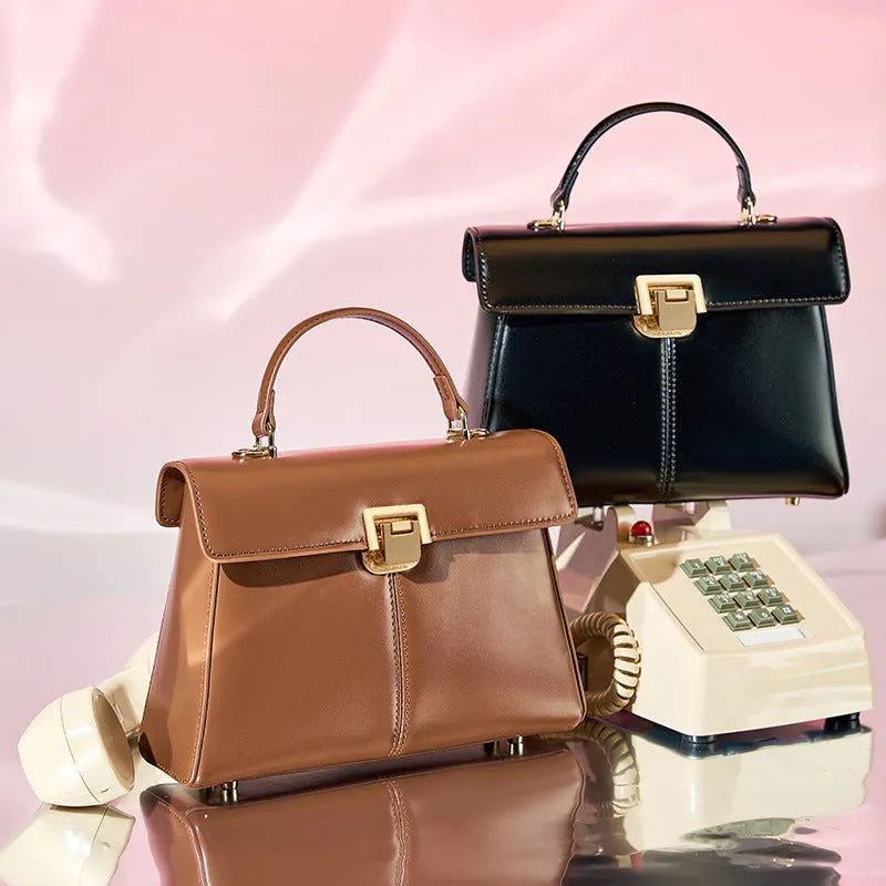 Black leather women's shoulder bag with vachette clasp showing horizontal square shape and adjustable strap