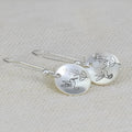 Silver glossy round women's earrings with bird and leaf motif