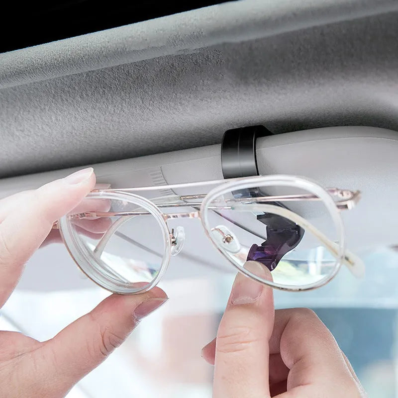 Black plastic multifunctional clip for car sun visor to hold sunglasses, tickets, and ID cards.