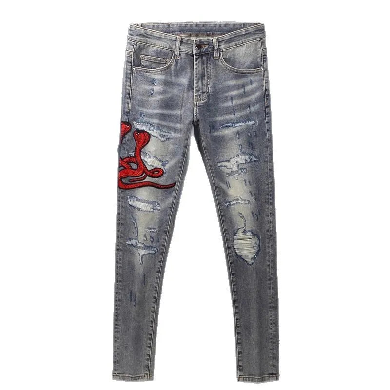 Slim fit light blue jeans with worn patches and embroidery on the legs, showing a washed-out colour.