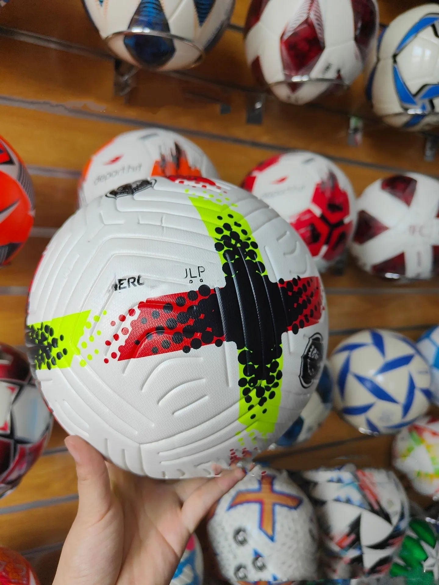Fluorescent green Size 5 PU football with seamless thermal adhesive patch construction on grass.