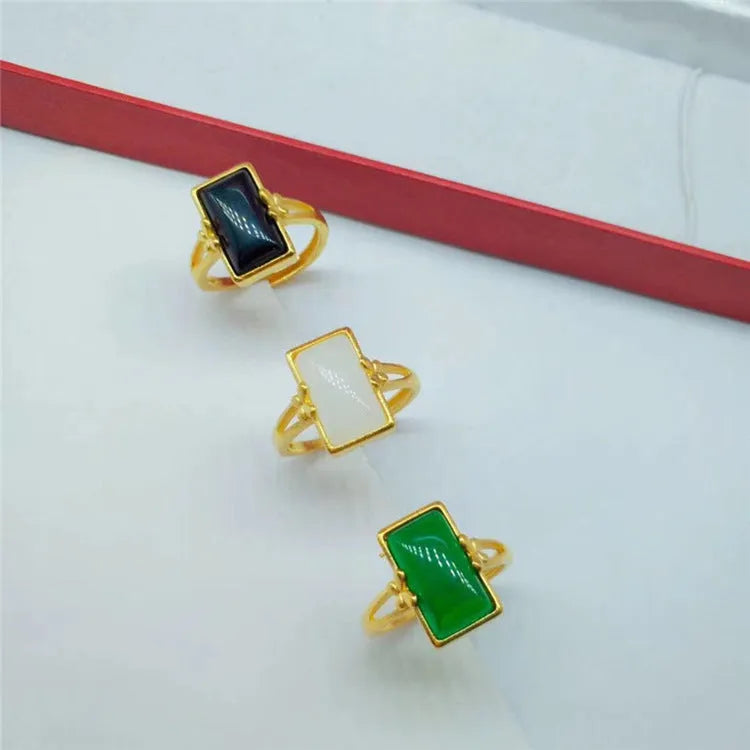 Gold-plated adjustable brass ring with a central inlaid gemstone, shown in black, green, and white colour options.