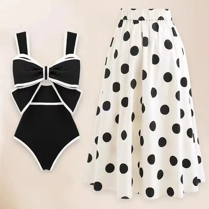 Women's black one-piece swimsuit with a white round skirt and bow detail on the front.