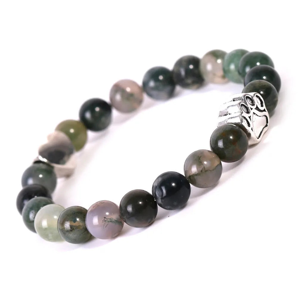 Close-up of a tiger's eye and Indian agate bead bracelet with a central geometric dog's paw charm on a wrist.